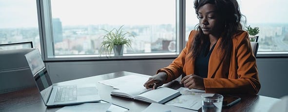 Woman reviewing documents at a desk by a window