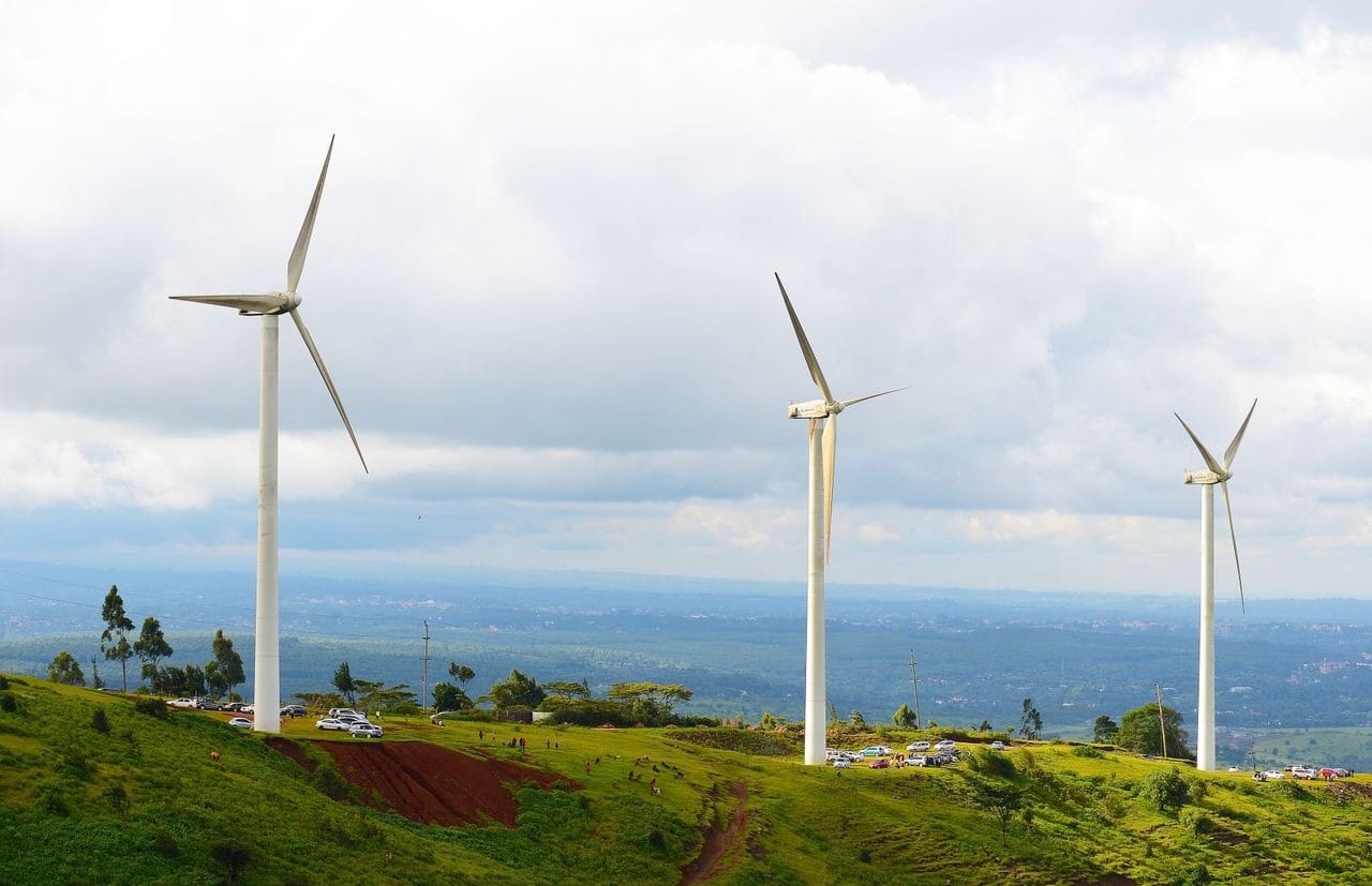 Wind turbines on a green hillside overlooking a valley